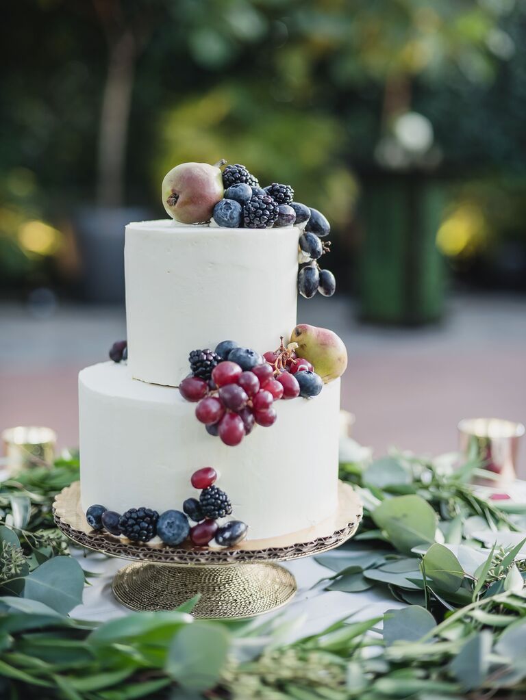 two-tier white wedding cake with purple grapes, blackberries, blueberries and miniature pears