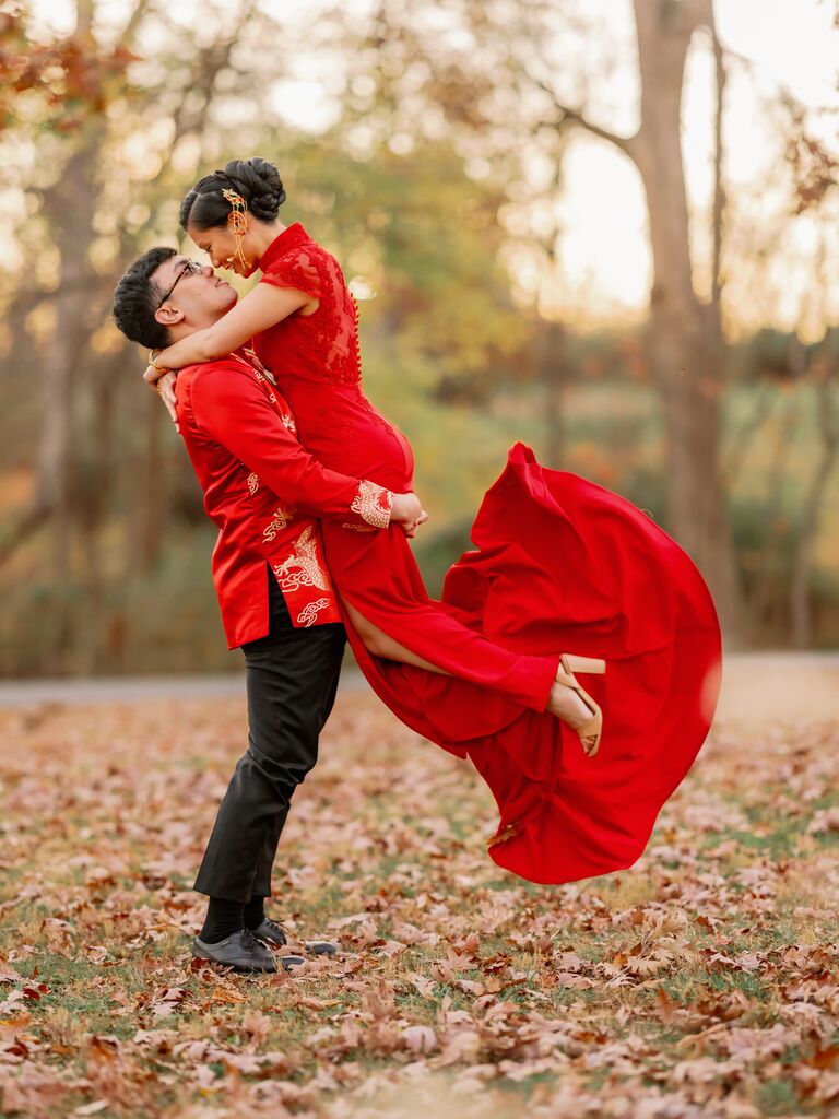 Bride and groom at Chinese wedding doing lift up pose in autumn field