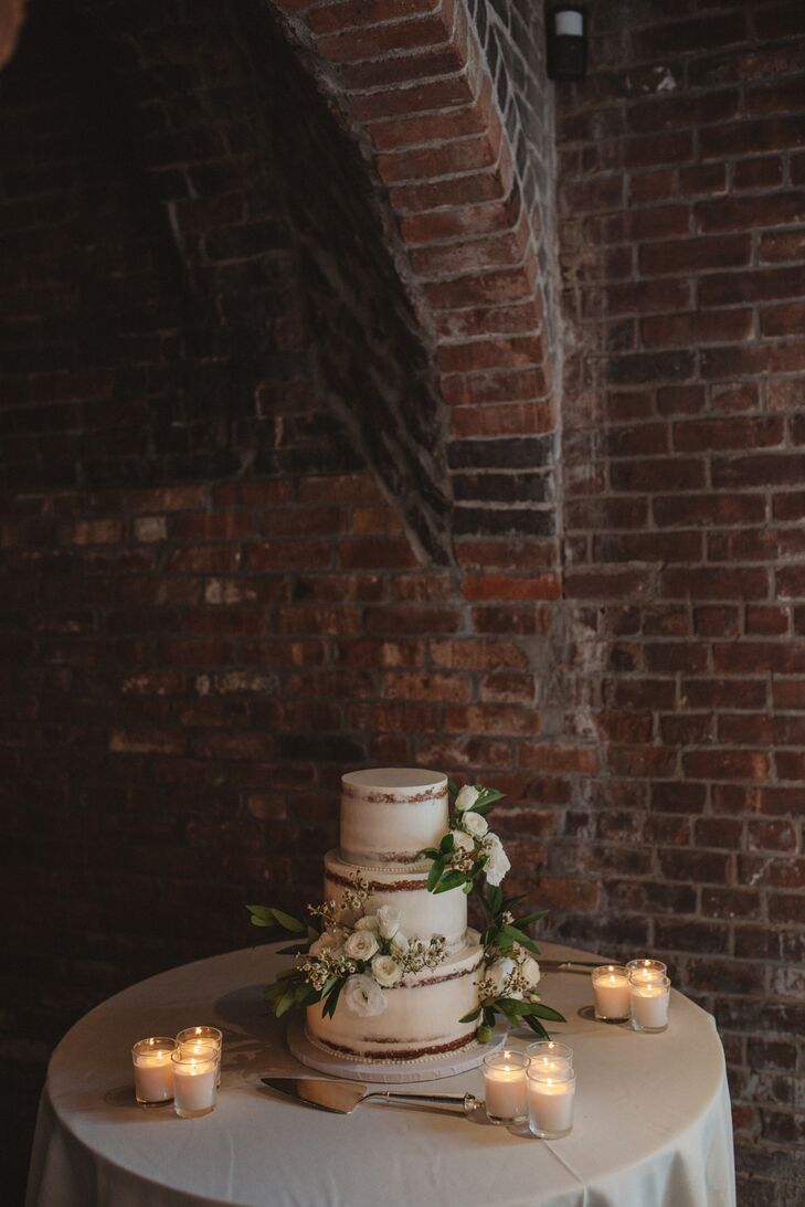 Sugar Lane Cake Shop of Nesconset, New York, created Nancy and Michael's three-tier, roughly frosted white cake with white ranunculus.