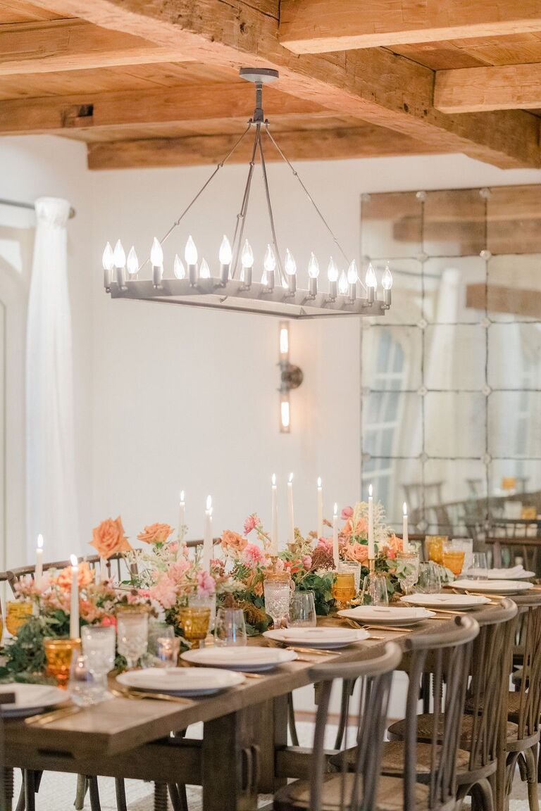 Rustic wedding reception with rectangular chandelier above farm table