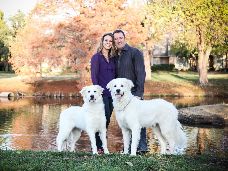 Couple posing in front of lake and autumn trees.