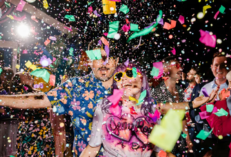 A wedding couple and guests on the dance floor with confetti