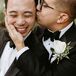 Two Grooms in Matching Classic Tuxedos and White Boutonnieres With Greenery