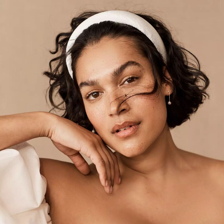 Model wears a chunky white headband in her hair. 