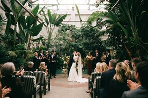 Bride and Groom Share First Kiss at Ceremony in Industrial Greenhouse Garden, Tropical and Greenery
