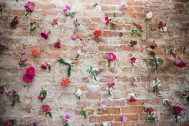 At the reception, a brick wall was decorated with individual flowers for a fun photo-booth backdrop. "The visual irony gave an elegant yet organic feel to the celebration," Andi says.
