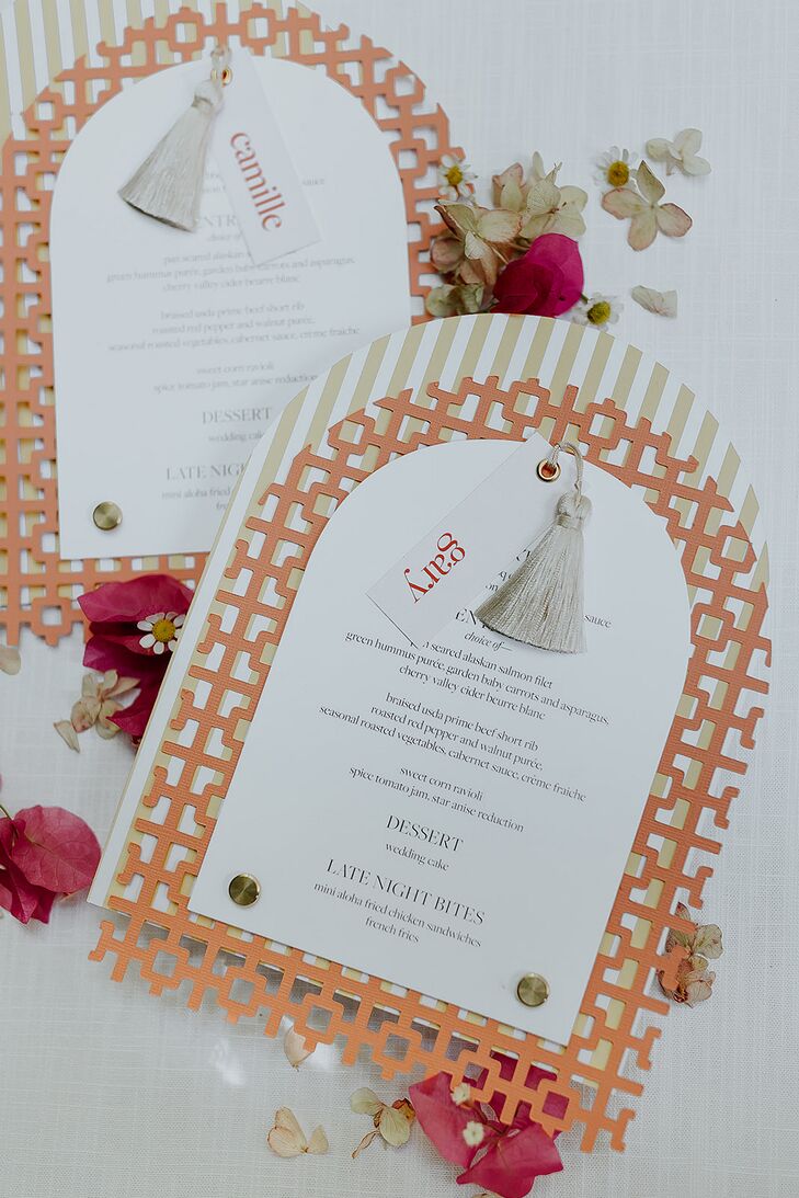 A custom, modern wedding reception menu design with a paper backing in orange inspired by a famous wall at the wedding venue: The Parker Palm Springs, with tassel details and name tags.