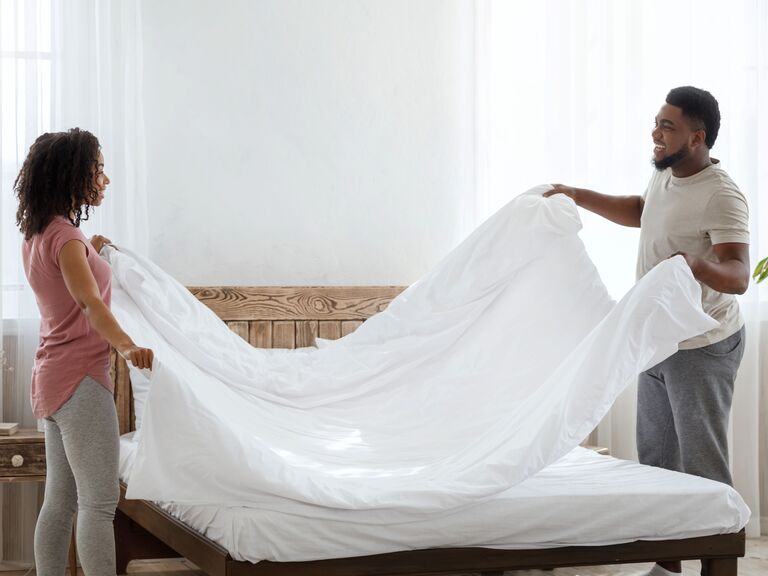 Couple making bed bedding registry checklist