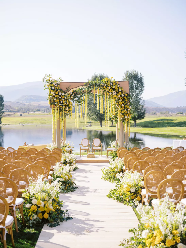 What a dreamy scene: yellow and white flowers cascade down the wedding arch and lead guests towards the altar.