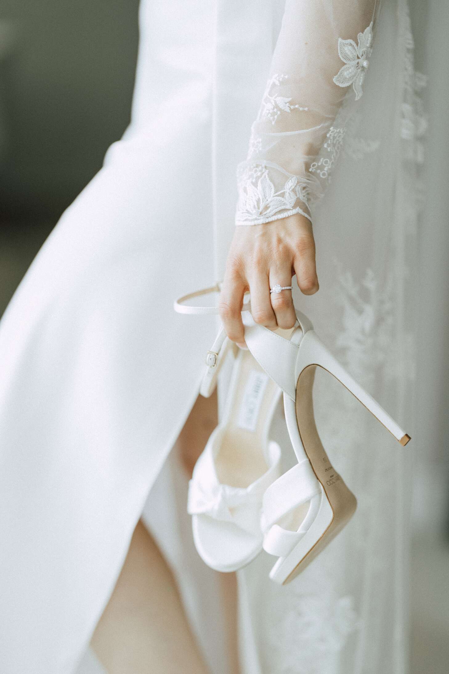 white dress with ivory shoes Bride Holding Satin Heels While in Her Long-Sleeved Floral Wedding Gown SPECIAL LABEL
