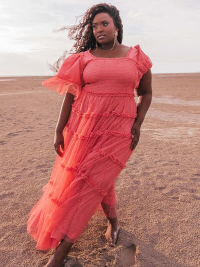 Model wearing a long tulle dress in a bright desert rose shade