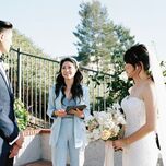 bride and groom stand outside at wedding ceremony with officiant