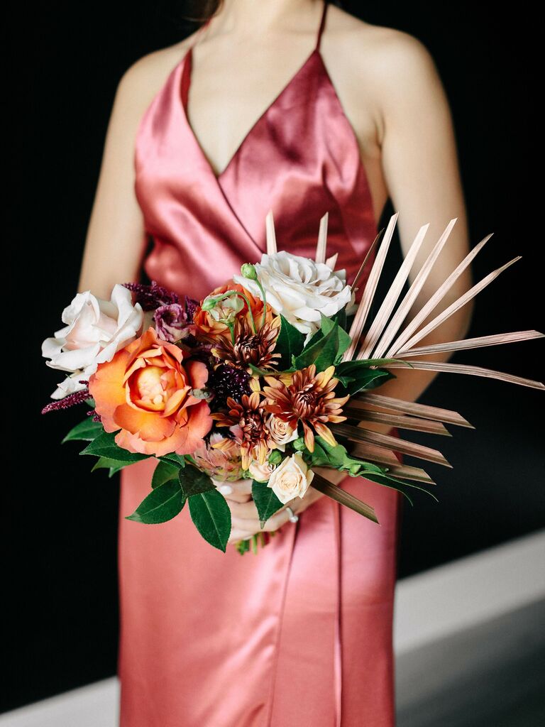 A bridesmaid holds this vibrant summertime bouquet.