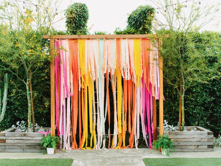 colorful wedding arch alternative made from paper streamers in pink, orange yellow and blue