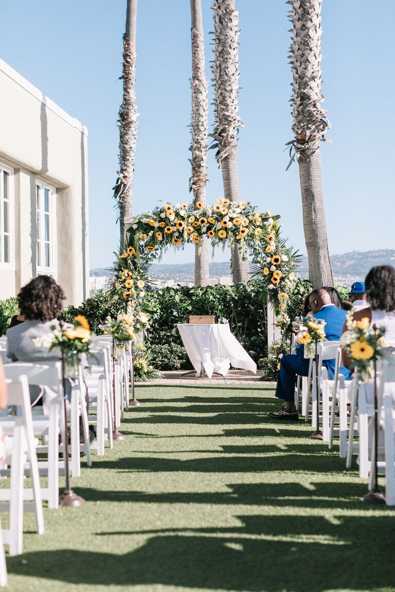 Oceanfront wedding ceremony with sunflower altar arch