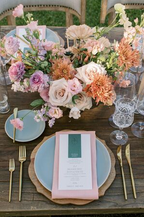 Pastel Place Setting With Pink Linens, Blue Chargers and a Low Colorful Centerpiece