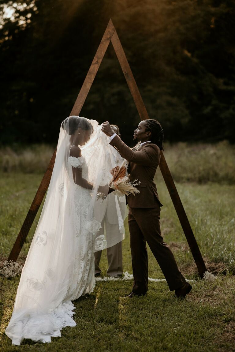 Groom lifting bride's veil during wedding ceremony
