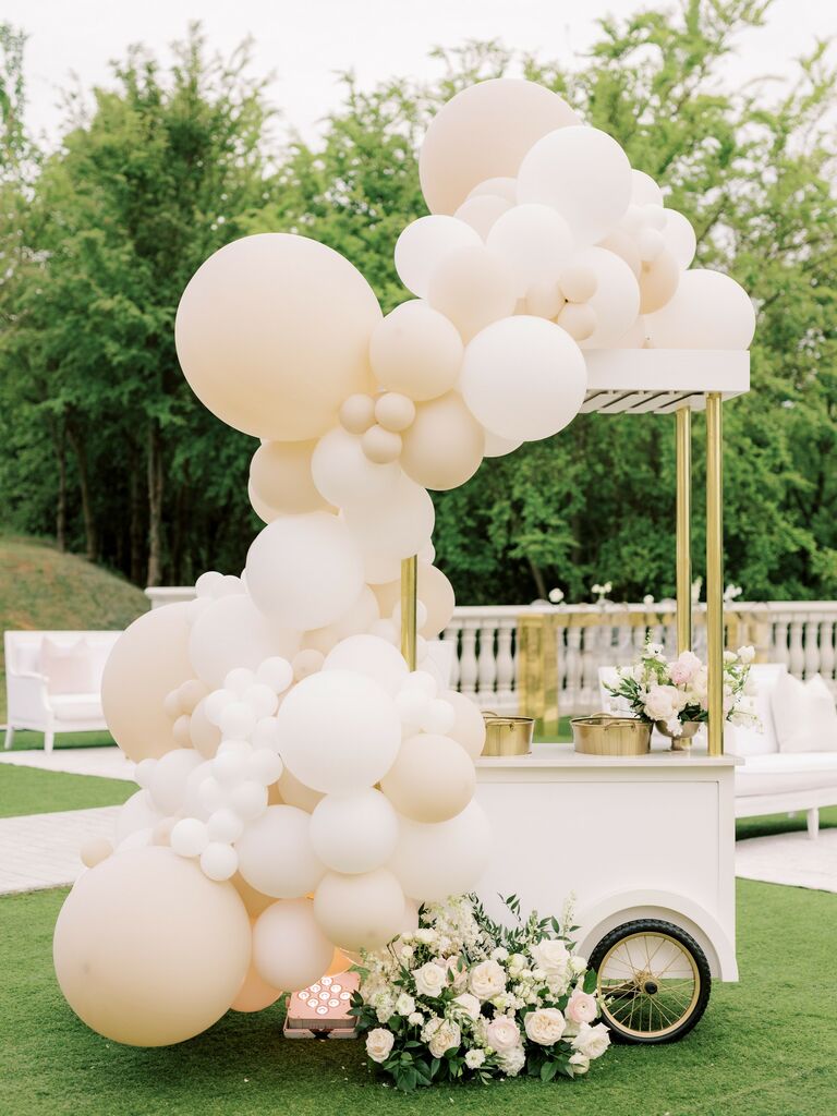 bridal shower drink cart decorated with balloon arch in neutral white and ivory colors