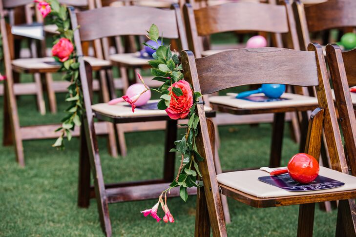 Caroline and Christopher's aisle decor matched the wedding arch and added extra color to the natural setting of St. Augstine Green in Rosemary Beach, Florida. Mini-arrangements of greenery, fuchsia garden roses and pink tuber roses accented every row of wooden folding chairs.