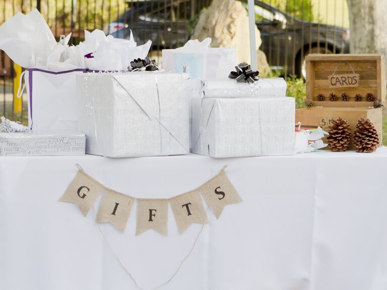 An assortment of wrapped gifts sits on a table at a wedding. 