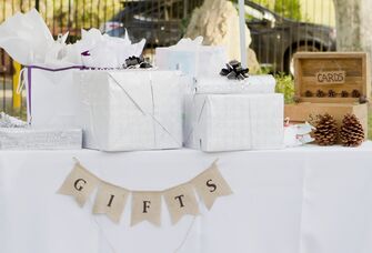 An assortment of wrapped gifts sits on a table at a wedding. 