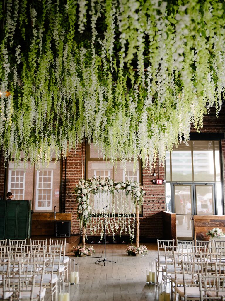 indoor wedding ceremony with white wisteria vines hanging from the ceiling