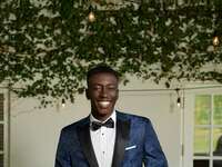 Groom wearing navy tuxedo with black pattern and black pants