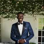 Groom wearing navy tuxedo with black pattern and black pants
