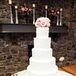 The couple chose a formal five-tiered white cake with alternating piping patterns on each layer topped with light pink roses.