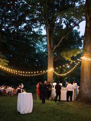 Outdoor Reception at Dusk Under String Lights With a Bar and Cocktail Tables