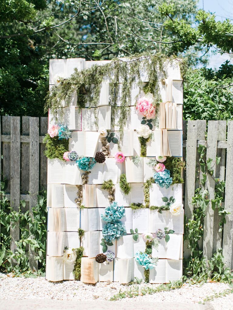 wedding backdrop made with open vintage books, pink and blue flowers with greenery