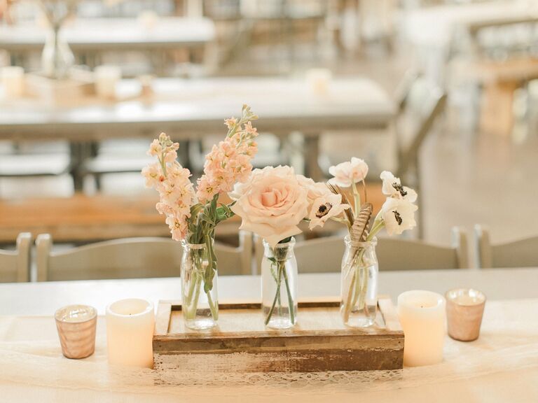 An elegant floral centerpiece of three small glass vases.