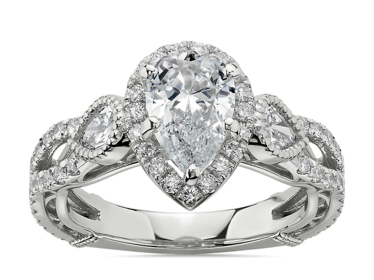 Pear cut center diamond with round diamond halo and pave diamond twisted band