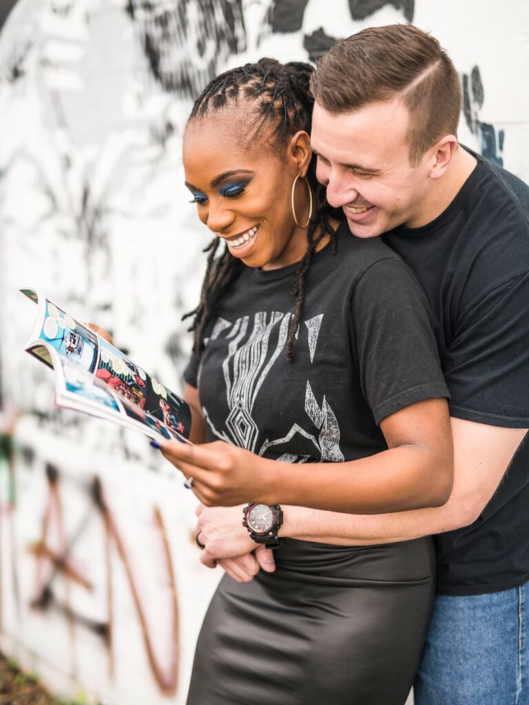 Couple smiles while flipping through a comic book together. 
