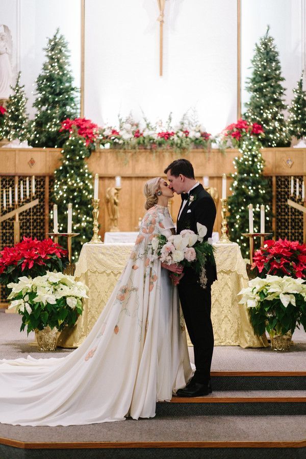 Couple sharing kiss in church surrounded by poinsettias
