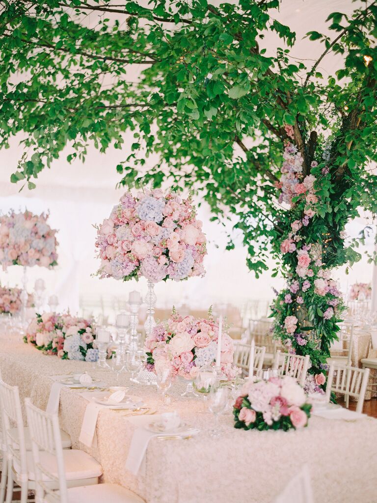 tall pastel wedding centerpiece with pink roses and blue hydrangeas displayed on glass stand