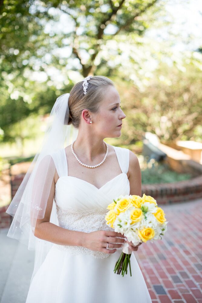 Britni's dress was an A-line Casablanca Bridal gown with straps and beading in the bodice. She accessorized with a pearl necklace and an embellished headband. She wore her hair in a chignon and paired her dress with an elbow-length veil for the ceremony.