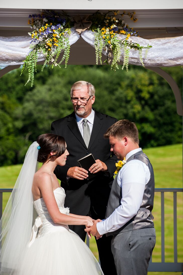 Haley and Jeremiah held hands in matrimony as they stood under the pavilion, with wildflowers and greenery decorating the top. Jeremiah had a charcoal gray vest that matched his pants, with a canary yellow and white flower boutonniere pinned to his outfit.