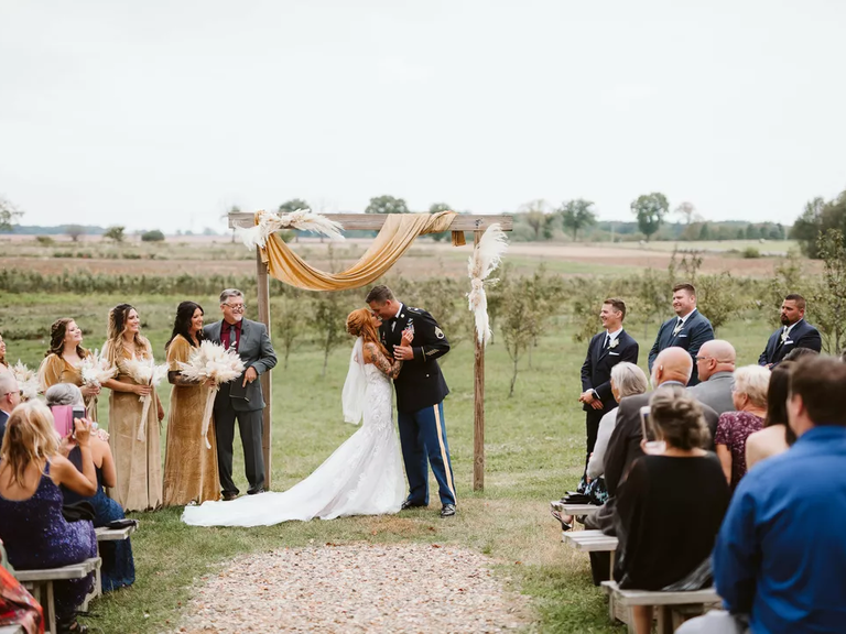 A bride and groom lean in for a kiss at this outdoor wedding ceremony.