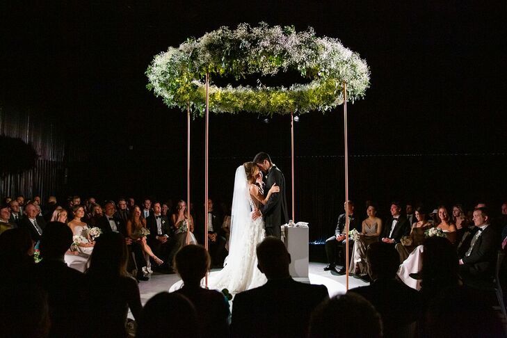 Couple standing under circular chuppah.
