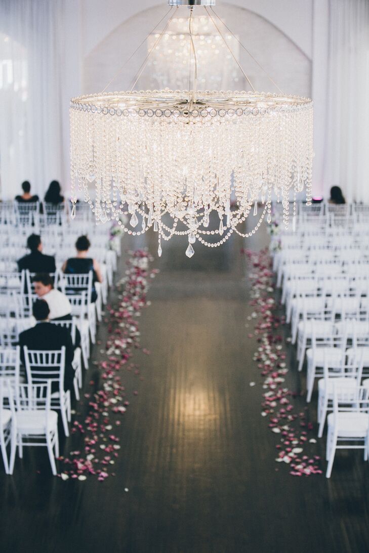 The all-white ceremony space was decorated with white chiavari chairs and rose petals.