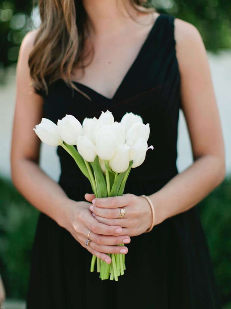 A bridesmaid holds a bouquet of white tulips.