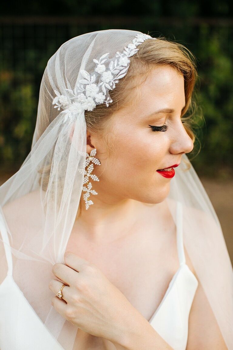 bride with strawberry blonde hair wears tulle juliet cap wedding veil featuring floral lace appliques