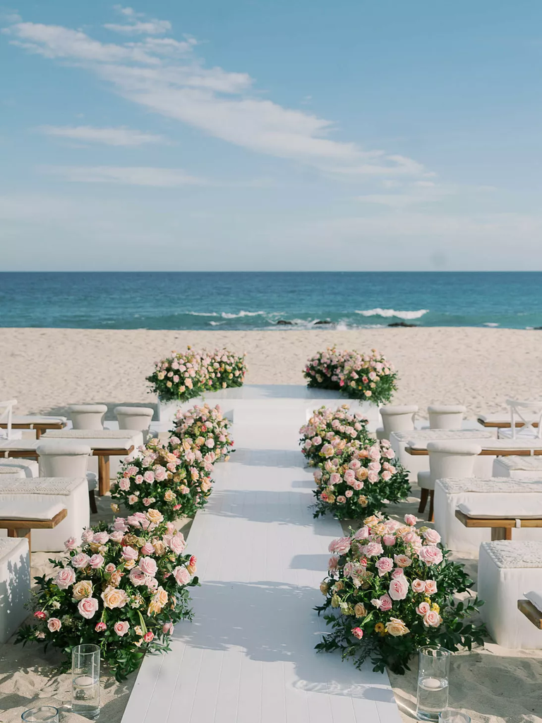 A gorgeous seaside wedding ceremony site, with pink roses along the aisle.