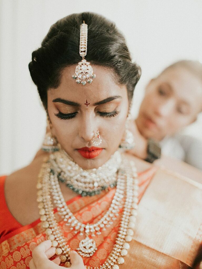 Indian bride wears beautiful headpiece and necklaces. 