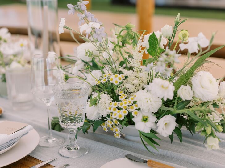 A Low Floral Centerpiece With White Flowers and Greenery on Dining Table