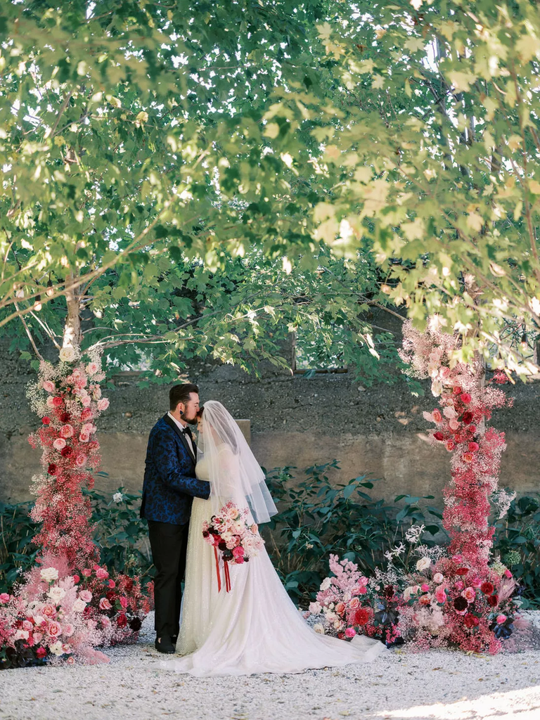 A couple share a tender moment among their dusty rose wedding ceremony decor.