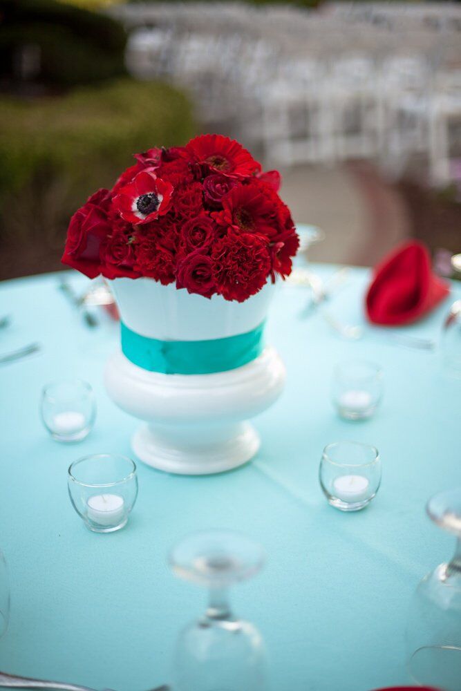 Deep red anemone flowers mixed with mums, carnations and roses were placed in large white vases tied with blue ribbon.