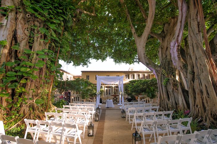 Melissa and Derek used the Addison's twin Banyan trees as the main decor for their wedding in Boca Raton, Florida. Rows of white folding chairs were met with navy fan programs as simple black lanterns lined the aisle. The couple's white fabric-draped chuppah stood out with the only florals along each post: white hydrangeas and roses.