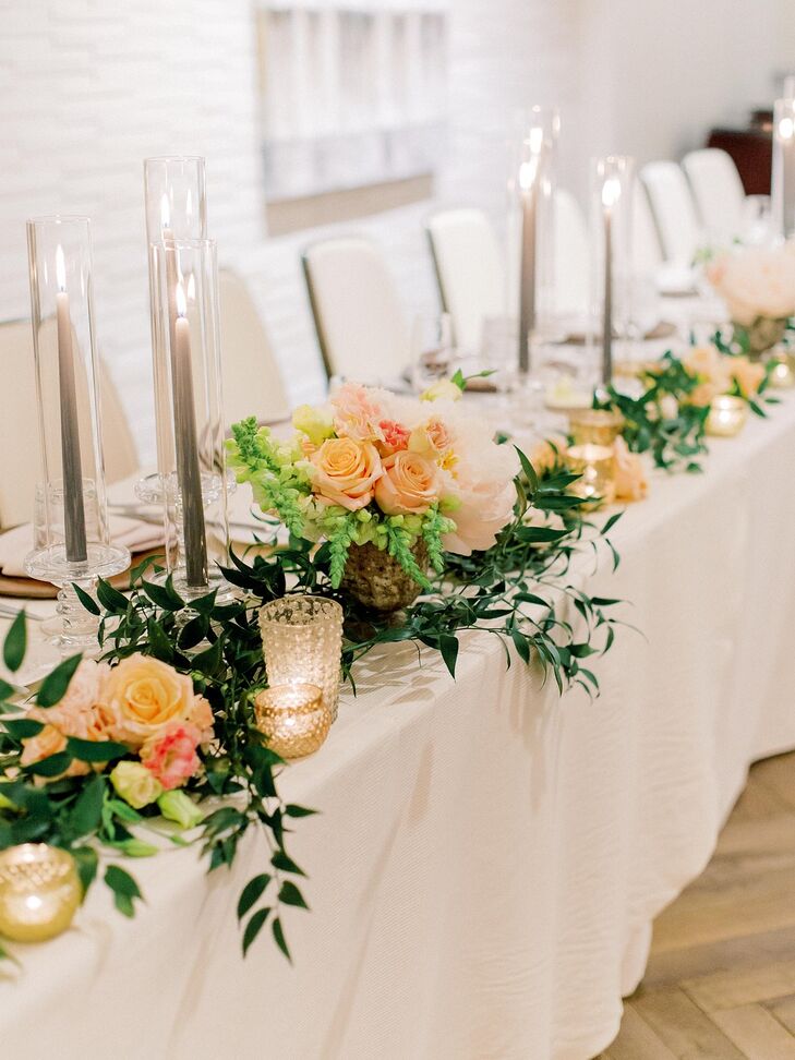 Romantic Head Table with Pink Flowers, Greenery Garland and Taper Candles in Glass Votives